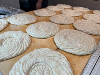 Traditional Uzbek round flatbreads are prepared for baking in a tandoor