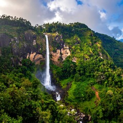 Obraz premium Majestic waterfall cascading down a dramatic mountainside, surrounded by lush greenery