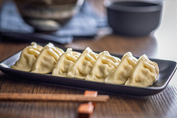 Traditional japanese gyoza dumplings on plate on wooden table.