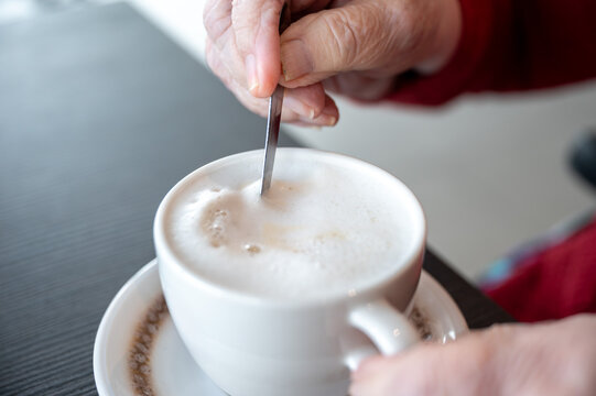 87 yo woman stirring in a cappuccino, Tienen, Belgium