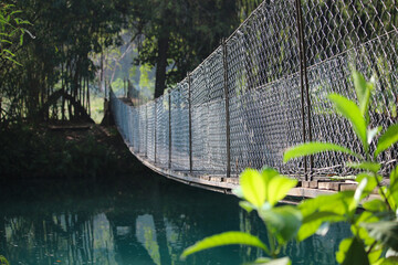 A view along a suspension bridge over an aquamarine river on a sunny morning in El Meco, Mexico