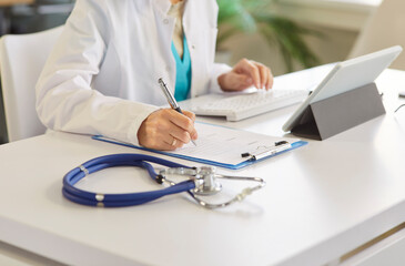 Medical professional, doctor or nurse hand writing in clipboard, typing on keyboard, working at desk with documentation and administrative tasks, healthcare record keeping in clinic office, planning
