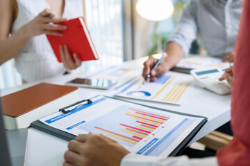 Three people are sitting at a table with papers and graphs in front of them. They are discussing something important, and it seems like they are trying to come up with a solution to a problem
