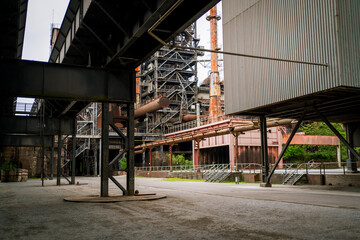 Fototapeta premium Wide-angle view of an abandoned industrial factory featuring rusted pipelines, steel beams, and scaffolding. A perfect scene for industrial design and urban decay themes.