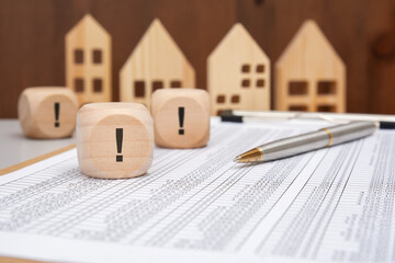 Wooden cubes with exclamation marks and pen on financial spreadsheet
