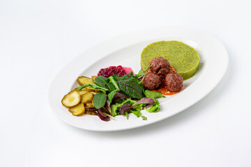 Meatballs with green puree, salad, and pickles