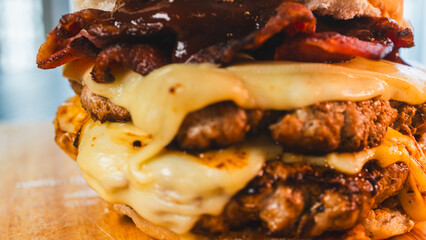 A massive and juicy double-patty burger, overflowing with crispy bacon and abundant melted cheese. This towering, indulgent creation is the ultimate comfort food, captured in all its delicious glory.