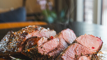 Freshly sliced, succulent roasted leg of lamb, releasing tempting steam. Served on a wooden board with aromatic rosemary and herbs, this juicy and perfectly cooked meat is the ultimate hearty meal.