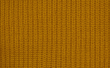 Close-up of warm mustard yellow knitted wool texture, cozy autumn winter fabric background
