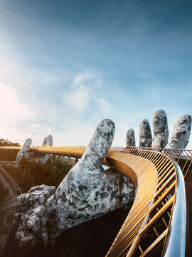 Vietnam landmark - Golden bridge in Ba na hills park Da nang resort, famous touristic attraction sightseeing destination: giant hands holding footbridge epic scenery