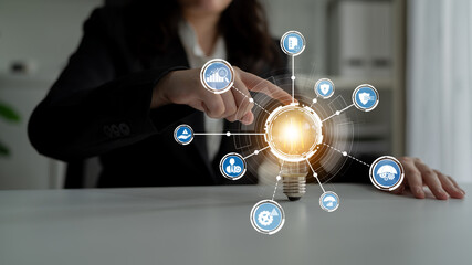 A businessperson interacts with a light bulb graphic surrounded by icons, symbolizing innovation...