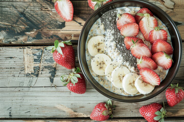 Healthy oatmeal bowl with fresh strawberries banana and chia seeds