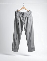 Gray pleated trousers hanging on a light wooden hanger against a plain white background