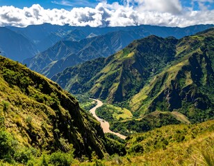 High-angle view of a verdant valley carved by a river, surrounded by rugged mountains under a partly cloudy sky
