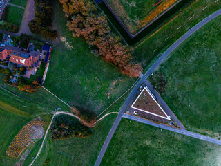 Aerial view of landscaped urban fringe triangular flat roofed structure anchors grassy park with...