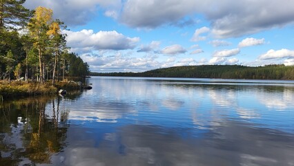 Calm lake reflecting a blue sky and autumn trees on a clear day in a serene natural setting