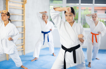 Obraz premium Female students of martial arts academy look at Kata karate teacher conducts classes and performs movements and fighting techniques together