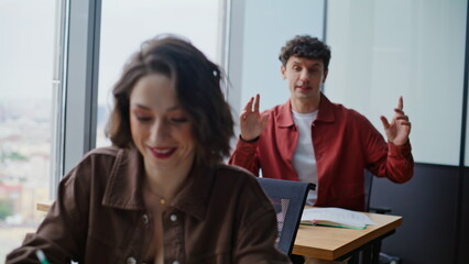 Closeup two students communicating at cabinet. Laughing people clapping hands