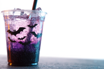 Halloween themed purple and black glitter drink with bats served in a clear plastic cup with a straw isolated on white background