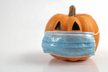 Pumpkin wearing a surgical mask a symbol of Halloween during the COVID-19 pandemic isolated on white