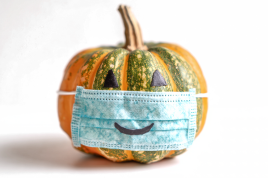 Festive pumpkin wearing a face mask a symbol of Halloween during the pandemic isolated on white
