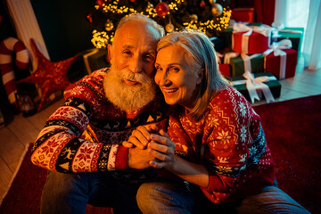 A loving elderly couple celebrate Christmas at home with a twinkling tree gifts warm sweaters and festive decorations