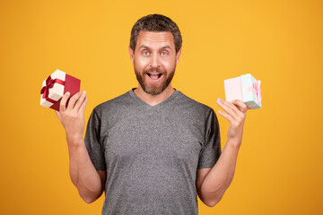 A surprised man holding a giftbox with a red ribbon. Gift box in hands. Man holding a gift, isolated background. Christmas gift in hands. Gift for Birthday Christmas or Valentines day. Fathers day.