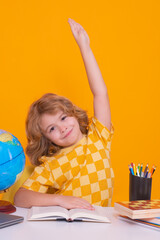 School child raising hands, willing to answer question. School child studying in classroom at elementary school. Kid studying on lesson on yellow isolated background.