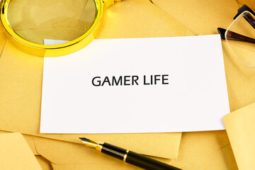 A white card reading GAMER LIFE rests amongst envelopes with a magnifying glass, reading glasses, and a pen near it. It conveys a comical, yet business-like approach