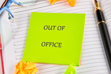 A day planner displays a vibrant out of office note. Also shown are glasses, a pen, and crumpled paper. This denotes a vacation from a Business in the City
