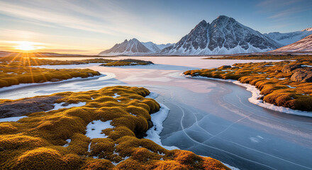 Obraz premium Winter Sunset Over Frozen Tundra River Leading to Snowy Mountains A breathtaking winter landscape captured at sunset, featuring the striking contrast between vibrant golden-orange moss/tundra grass 