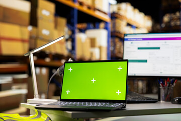 Empty warehouse depot running green screen on computer display, handling order processing and shipping e-commerce cargo products. Storage room with industrial racks and shelves.