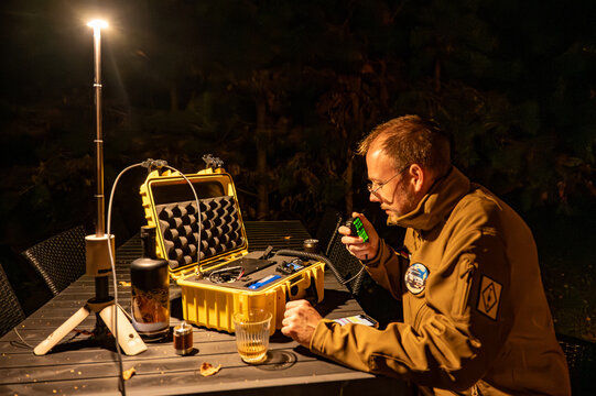 Amateur radio operator in the forest at night, sitting at a table with a portable HF Go-Box setup, communicating off-grid during an outdoor ham radio operation