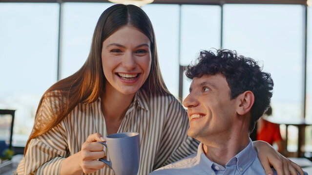 Positive colleagues sharing coffee cups talking at work break in office closeup