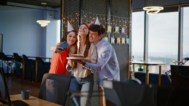 Photographing coworkers celebrating birthday having fun at festive office agency