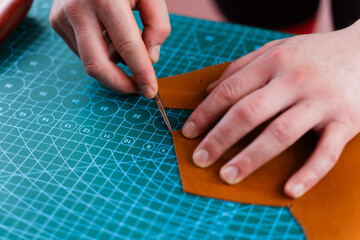 Craftsman refines leather edges with trimming tool, ensuring smooth curves and clean lines....