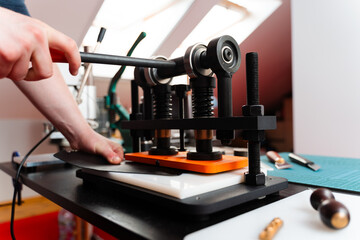 Leather pressing provides strength and detail to handmade designs, creating premium results for wallets, belts, and accessories. Craftsman uses press machine to imprint patterns into leather.