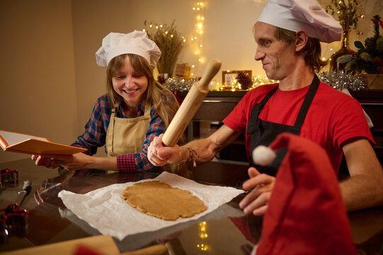 Joyful Christmas Kitchen Bake: Couple In Chef Hats Rolling Dough Together For Festive Cookies And Pie - Powered by Adobe