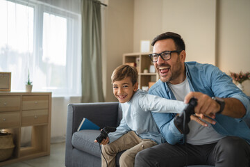 Excited dad and son enjoy while play video games at home