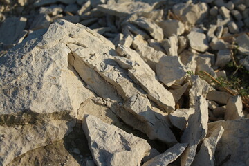 Rough light-colored stone fragments illuminated by strong sunlight creating deep shadows