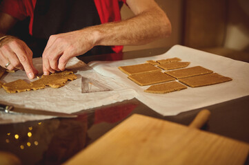 Home Baker Rolls And Cuts Dough On Parchment, Creating Small Rectangular Pieces For Baking In Warm Kitchen