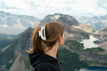 A woman gazes at a scenic mountain landscape with lakes