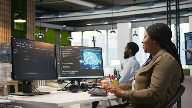 Female software developer using artificial intelligence to optimize performance and forecast issues. Woman in office training machine learning models using computer, camera A