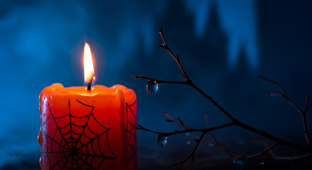 Eerie Orange Candle with Spiderweb and Water Droplets on Branch Against Blue Fog
