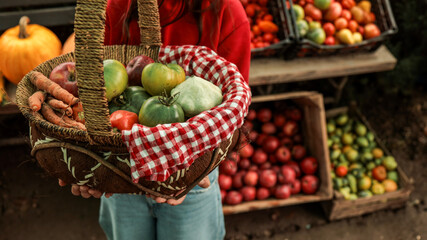 Person holding a basket filled with fresh produce at a farmer's market.