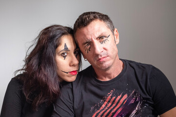 Obraz premium Husband and wife with face made up for Halloween portraits on light background. The man and woman are thirty-eight years old and of Caucasian origin