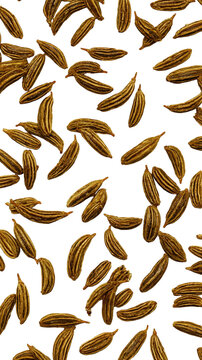 Aromatic whole dried cumin seeds scattered on a white surface.