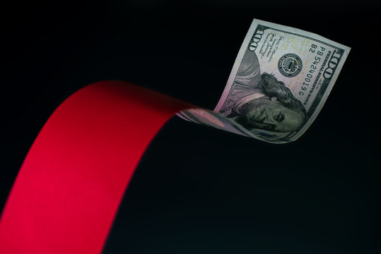 US 100 dollar bill floating with red ribbon on dark background. finance and economic