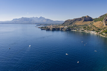 Obraz premium Capo Zafferano Italian coastal promontory and lighthouse aerial drone view by the Tyrrhenian Sea in Bagheria, Sicily Italy with rugged cliffs lush Mediterranean flora crystal clear water