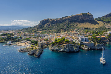 Fototapeta premium Sant Elia bay beach in Porticello town, Santa Flavia, Sicily, Italy, aerial drone view of Sicilian turquoise waters, rocky cliffs, colorful houses, and Mediterranean coastline panorama in Bagheria